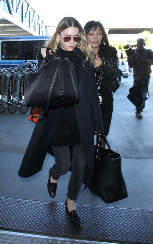 Ashley Olsen, tout de noir vêtue avec un manteau et deux sacs en cuir The Row à l'aéroport de Los Angeles, le 23 décembre 2014.
