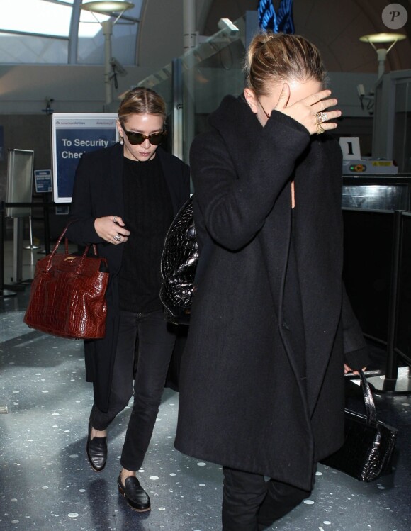 Les jumelles Mary-Kate et Ashley Olsen arrivent a l'aeroport de Los Angeles, le 14 novembre 2013. Ashley est celle qui porte un sac rouge. 