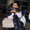 Ariana Grande se cache des photographes à son arrivée à l'aéroport de LAX à Los Angeles, le 3 juillet 2015