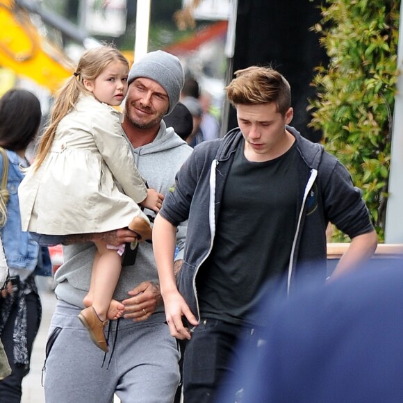 Exclusif - Prix Spécial - David Beckham sort déjeuner au restaurant Grainger & Co à Londres avec ses enfants Harper et Brooklyn. Les première images montrent que David Beckham n'est pas seulement une star du football ou de la mode. Il est un papa attentionné et câlin avec la jeune Harper. Il s'est aperçu que la petite a perdu une chaussure et la porte pour protéger son petit pied.  