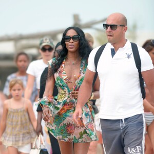 Naomi Campbell, habillée d'une robe Blumarine (collection printemps-été 2015) et de sandales Alaïa, arrive au Club 55 à Ramatuelle, commune voisine de Saint-Tropez. Le 23 juillet 2015.