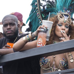 Rihanna et Lewis Hamilton (casquette bordeaux à l'envers, en arrière-plan) participent à la parade du Grand Kadooment lors du Crop Over Festival, à la Barbade. Bridgetown (capitale de la Barbade), le 3 août 2015.