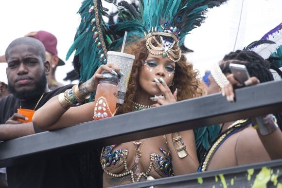 Rihanna et Lewis Hamilton (casquette bordeaux à l'envers, en arrière-plan) participent à la parade du Grand Kadooment lors du Crop Over Festival, à la Barbade. Bridgetown (capitale de la Barbade), le 3 août 2015.