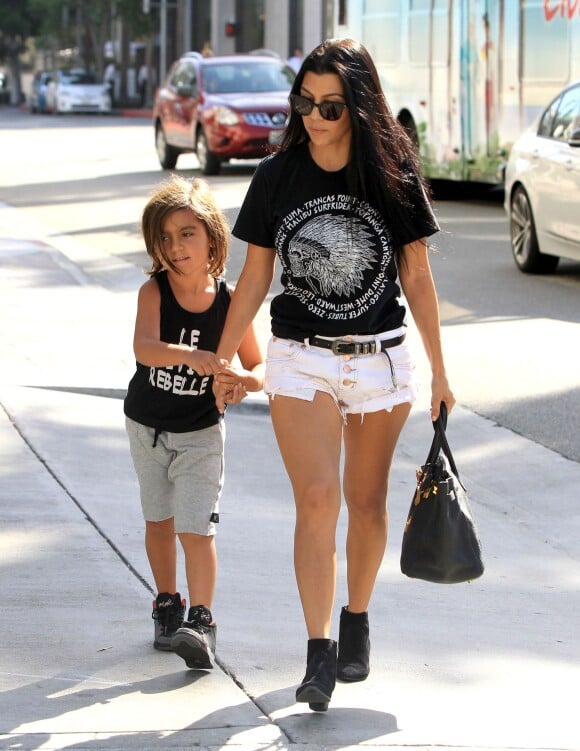 Kourtney Kardashian va faire du shopping avec son fils Mason à Beverly Hills, habillée d'un t-shirt noir, d'un mini-short blanc One Teaspoon et de bottines Saint Laurent. Des lunettes de soleil, une ceinture Saint Laurent et un sac Hermès (modèle Birkin) accessoirisent sa tenue. Le 3 août 2015.