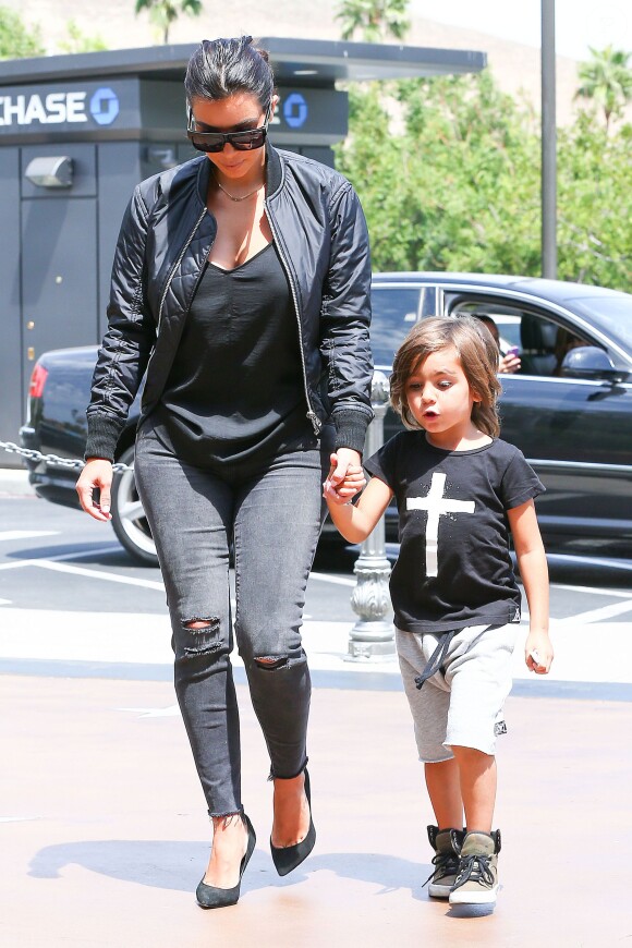 Avec sa tata Kim, pour aller au cinéma Mason porte un tee shirt noir imprimé d'une croix, un bermuda gris et des sneakers couleur kaki, le 19 août 2015 à Los Angeles