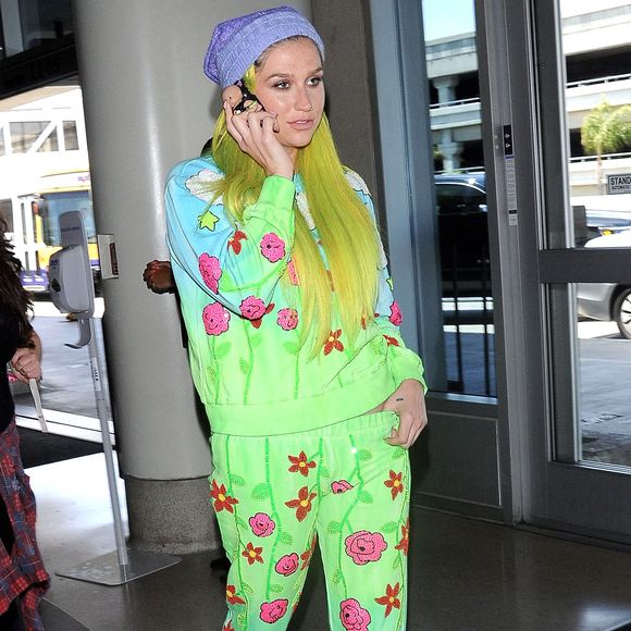 Kesha, les cheveux jaune, arrive à l'aéroport de LAX pour prendre l’avion. La coque de téléphone de Kesha est une poupée en 3D! Le 4 juillet 2015
