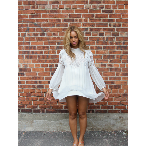 Beyoncé, ravissante dans son top blanc en dentelle et coton (collection automne-hiver 2015), sa jupe assortie Chloé et des sandales Chanel, pose devant un mur de briques. Photo publiée le 1er septembre 2015.