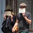 Emma Stone et son petit-ami Andrew Garfield se cachent le visage avec chacun un message en sortant d'un déjeuner au Cafe Cluny à New York, le 17 juin 2014. Sur leurs papiers on peut lire qu'ils n'ont pas besoin de publicité mais que les associations mentionnées en ont vraiment besoin.