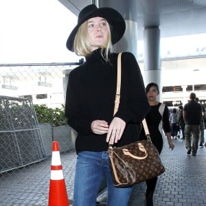 Elle Fanning à l'aéroport LAX de Los Angeles, porte un chapeau et un pull à col roulé noirs, un sac Louis Vuitton (modèle Speedy Bandoulière), un jean 3x1 et des chaussures Stella McCartney. Le 4 novembre 2015.