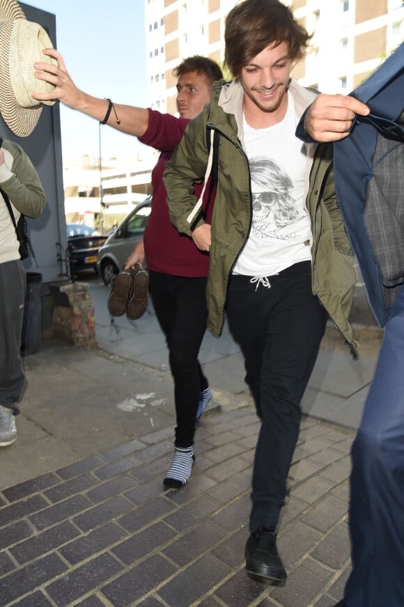 Le membre du groupe One Direction Louis Tomlinson sort avec des filles de l'hôtel Soho à Londres, le 23 avril 2015, où ils ont passé la nuit.