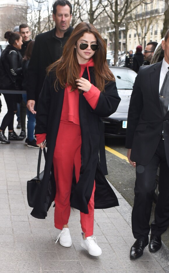 Selena Gomez à Paris, porte un manteau en laine Jenni Kayne (collection printemps 2016), un pull à capuche et un jogging Vetements, un sac Louis Vuitton (modèle Trocadéro) et des baskets blanches. Paris, le 8 mars 2016.