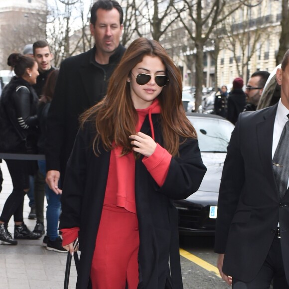 Selena Gomez à Paris, porte un manteau en laine Jenni Kayne (collection printemps 2016), un pull à capuche et un jogging Vetements, un sac Louis Vuitton (modèle Trocadéro) et des baskets blanches. Paris, le 8 mars 2016.