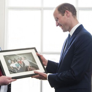 Le prince William, duc de Cambridge, était le 13 mai 2016 en visite dans les locaux de l'organisation "The Passage", qui porte assistance aux sans-abri, à Londres. A l'occasion de sa visite, il a reçu en cadeau une photo qu'il ne connaissait pas datant de sa visite en 1994 au même endroit avec sa mère la princesse Diana et son frère le prince Harry.