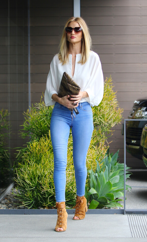 Rosie Huntington-Whiteley à Los Angeles, porte une blouse blanche, un jean PAIGE®, une pochette en python Givenchy et des chaussures Gianvito Rossu (modèle Brooklyn). Le 9 juin 2016.