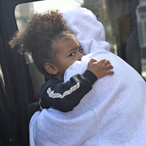 Kim Kardashian, cachée par ses vêtements, et sa fille North sortent de son appartement à New York, le 6 octobre 2016. Les photographes ne l'avaient pas vue depuis son retour précipité de Paris après son agression.
