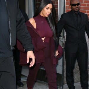 Kim Kardashian habillée de la tête aux pieds en bordeaux avec un haut très transparent à la sortie d'un immeuble à New York, le 15 février 2017.