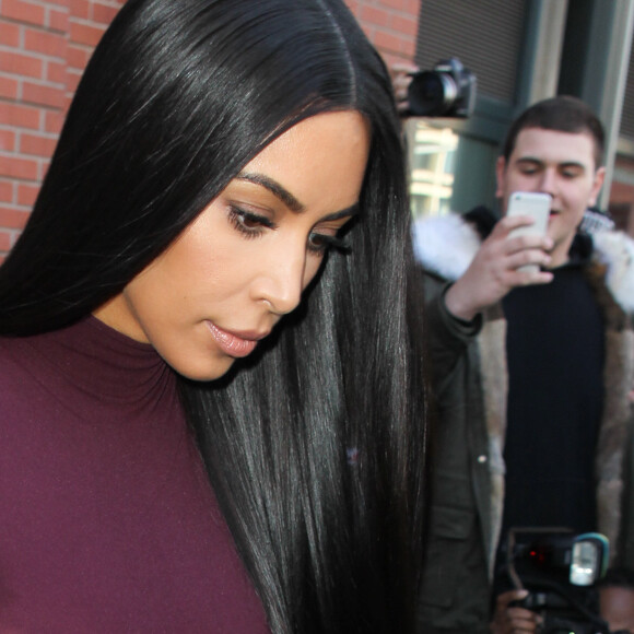 Kim Kardashian habillée de la tête aux pieds en bordeaux avec un haut très transparent à la sortie d'un immeuble à New York, le 15 février 2017.