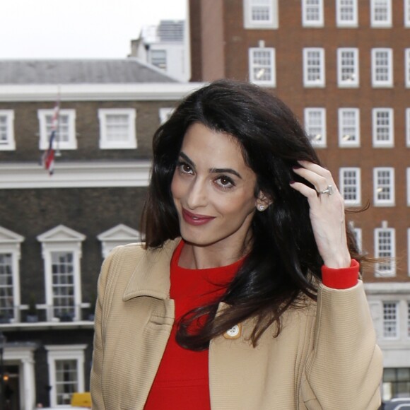 Amal Alamuddin Clooney, enceinte, arrive à Chatham House à Londres, vêtue d'un manteau beige Haute Couture Pierre Balmain (vers 1965), d'une robe rouge Haute Couture Christian Dior (collection automne-hiver 1972), d'un sac Altuzarra et de chaussures Oscar de la Renta. Le 29 mars 2017.