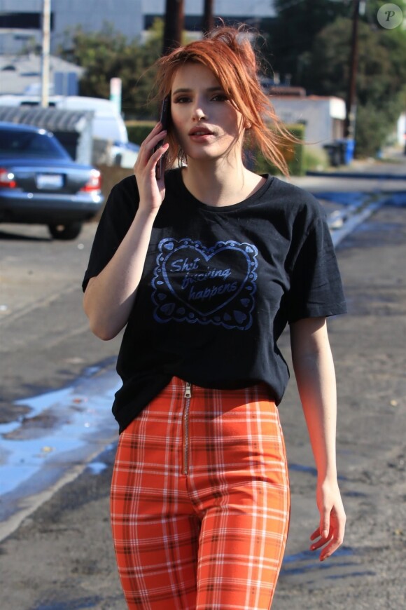 Bella Thorne discute au téléphone dans les rues de Studio City, le 19 décembre 2017  Actress Bella Thorne rocks a quirky outfit while out for lunch in Studio City. Bella was rocking a black t-shirt, a pair of orange plaid pants and a pair of striped sneakers. Bella's shirt had 'Sht Fcking Happens' written on the front. 19th december 201719/12/2017 - Los Angeles