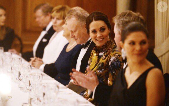 La duchesse Catherine de Cambridge, enceinte et en Erdem, lors d'un dîner à l'ambassade de Grande-Bretagne à Stockholm le 30 janvier 2018, avec à sa droite l'acteur Stellan Skarsgard et en discussion avec l'ambassadeur David Cairns.