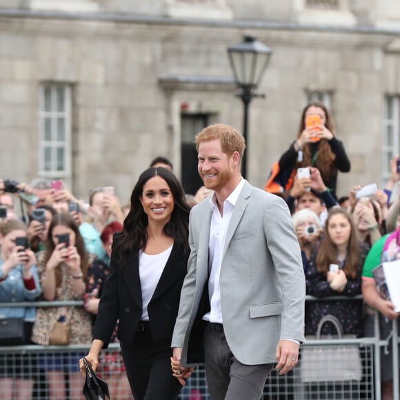 Le prince Harry, duc de Sussex et sa femme Meghan Markle, duchesse de Sussex saluent la foule lors de leur visite au collège de la trinité à Dublin le 11 juillet 2018.