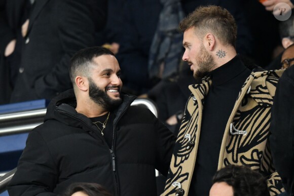 Malik Bentalha et Matt Pokora (M. Pokora) dans les tribunes du parc des Princes lors du match de football de ligue 1, opposant le Paris Saint-Germain (PSG) contre l'Olympique de Marseille (OM) à Paris, France, le 17 mars 2019. Le PSG a gagné 3-1.