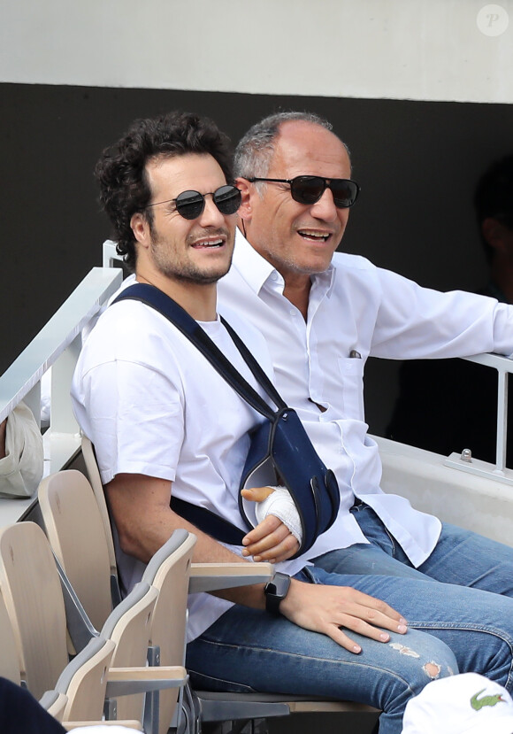 Amir Haddad (le bras gauche dans le plâtre après être tombé de scène pendant un concert à Aubagne) et son père René-Mikhael Haddad dans les tribunes des internationaux de tennis de Roland Garros à Paris, France, le 27 mai 2019. © Jacovides-Moreau/Bestimage