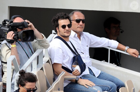 Amir Haddad (le bras gauche dans le plâtre après être tombé de scène pendant un concert à Aubagne) et son père René-Mikhael Haddad dans les tribunes des internationaux de tennis de Roland Garros à Paris, France, le 27 mai 2019. © Jacovides-Moreau/Bestimage