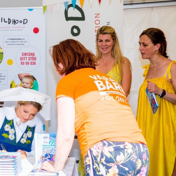 La princesse Madeleine de Suède en séance de dédicaces de son livre pour enfants Stella och hemligheten (Stella et le Secret) sur le parvis du palais royal à Stockholm, le 6 juin 2019, le jour de la Fête nationale.