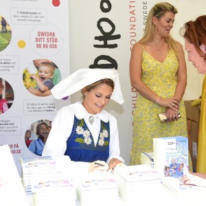 La princesse Madeleine de Suède en séance de dédicaces de son livre pour enfants Stella och hemligheten (Stella et le Secret) sur le parvis du palais royal à Stockholm, le 6 juin 2019, le jour de la Fête nationale.