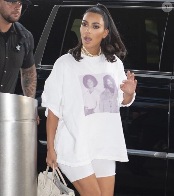 Kim Kardashian porte un t-shirt avec Michael Jackson et Prince à son arrivée à l'aéroport JFK à New York, le 25 juin 2019. Elle porte un cycliste blanc et des baskets Yeezy.