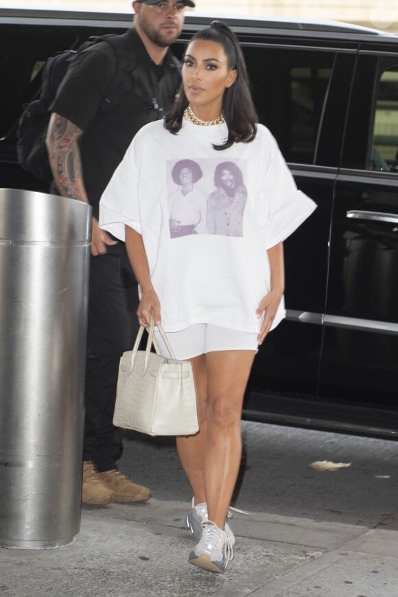 Kim Kardashian porte un t-shirt avec Michael Jackson et Prince à son arrivée à l'aéroport JFK à New York, le 25 juin 2019. Elle porte un cycliste blanc et des baskets Yeezy.