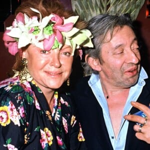 Archives - La chanteuse Régine avec Serge Gainsbourg et sa compagne Bambou chez Régine, à la soirée Carnaval des Îles. Le 9 mars 1988.