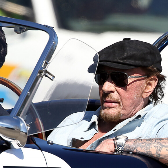 Johnny Hallyday accompagné de Maxim Nucci (Yodelice), arrive au restaurant "Soho House" à Malibu, au volant de son cabriolet AC Cobra marqué de son chiffre porte-bonheur, le numéro 7, Malibu, le 09 mars 2017.