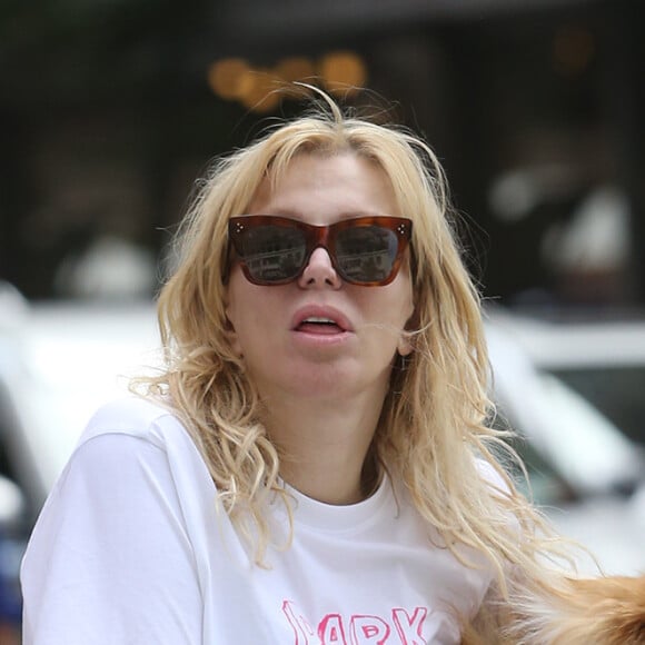 Exclusif - Courtney Love est captivée par son téléphone lors d'un petit déjeuner en terrasse avec son chien à New York le 8 septembre 2019.