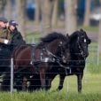 Le prince Philip, duc d'Edimbourg, aux rênes de sa calèche tirée par deux chevaux noirs, avec deux palefreniers à Windsor, Royaume Uni, le 15 avril 2019.