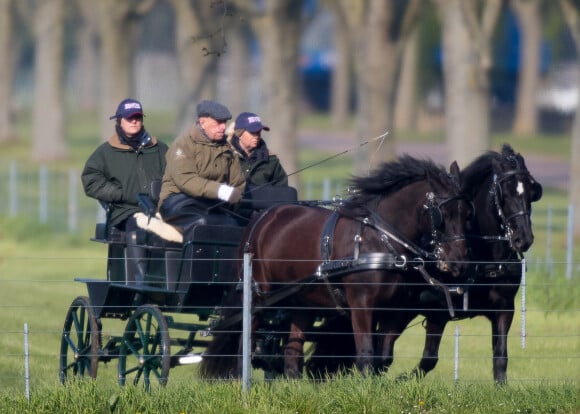 Le prince Philip, duc d'Edimbourg, aux rênes de sa calèche tirée par deux chevaux noirs, avec deux palefreniers à Windsor, Royaume Uni, le 15 avril 2019.