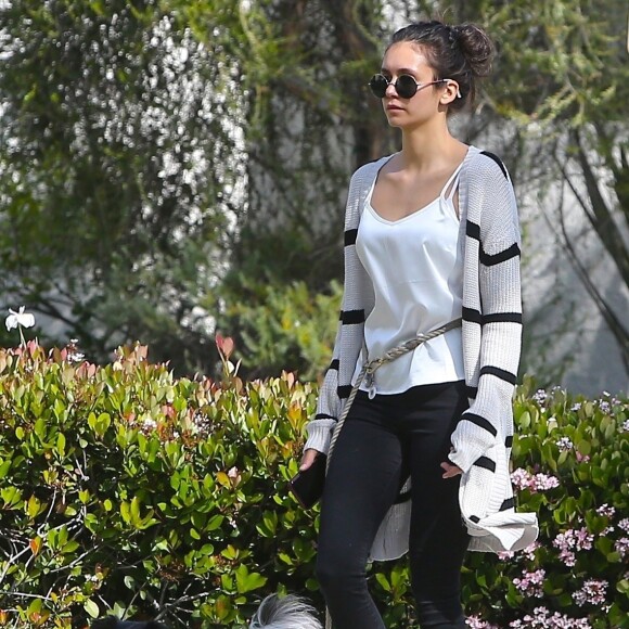 Concentrée sur son téléphone, Nina Dobrev oublie de ramasser les déjections de son chien lors de sa promenade à Beverly Hills, le 7 avril 2020.