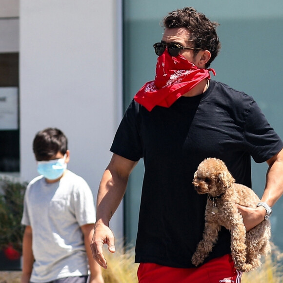 Exclusif - Orlando Bloom passe un moment complice avec son fils Flynn à Brentwood le 19 mai 2020. En marge d'une balade avec le chien, ils se posent sur un banc pour écouter de la musique sur le téléphone d'Orlando.