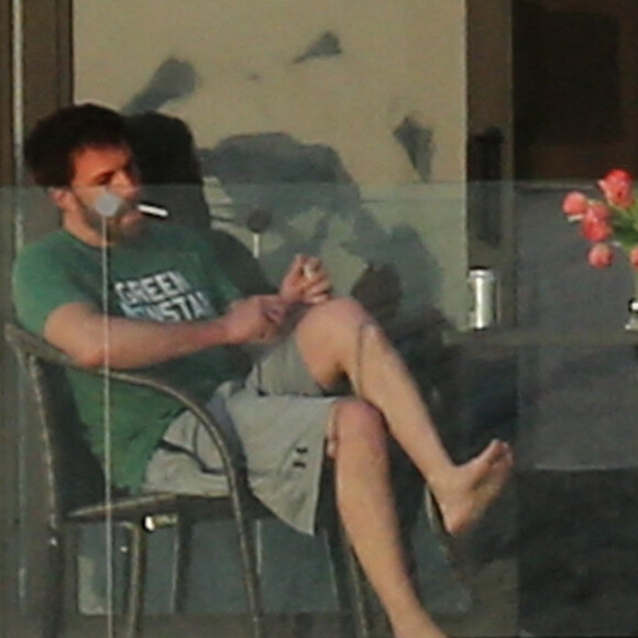 Ben Affleck fume une cigarette sur le balcon de la maison qu'il loue avec Jennifer Lopez à Miami le 25 mai 2021. 