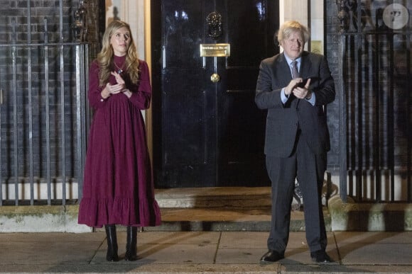 Le premier ministre Boris Johnson et sa compagne Carrie Symonds applaudissent devant le 10 Downing Street pour rendre hommage au capitaine Tom Moore, vétéran et héros du confinement décédé à l'âge de 100 ans. Londres, le 3 février 2021
