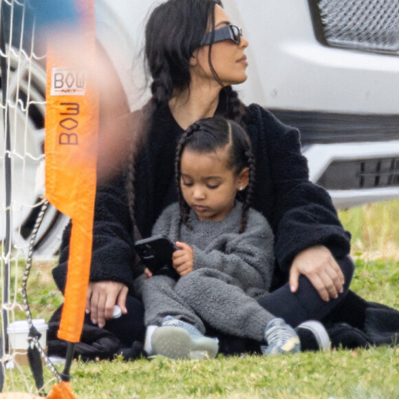 Kim Kardashian regarde le match de football de son fils Saint, assise sur la pelouse avec sa fille Chicago à Los Angeles le 3 avril 2022. 