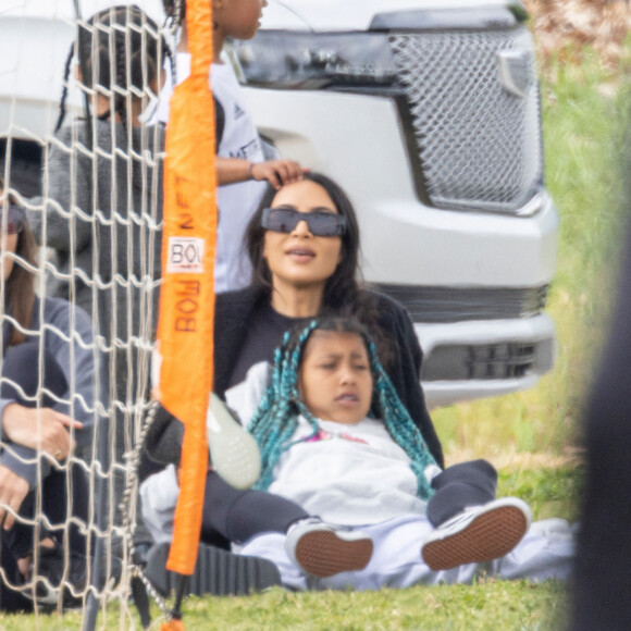 Kim Kardashian regarde le match de football de son fils Saint, assise sur la pelouse avec sa fille North à Los Angeles le 3 avril 2022. 