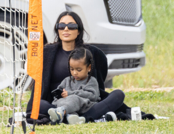 Kim Kardashian regarde le match de football de son fils Saint, assise sur la pelouse avec sa fille Chicago à Los Angeles le 3 avril 2022. 