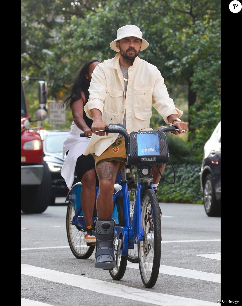 Jesse Williams fait du vélo en portant une attelle de pied à New York le 12 septembre 2021. L'acteur était accompagné d'une mystérieuse inconnue.