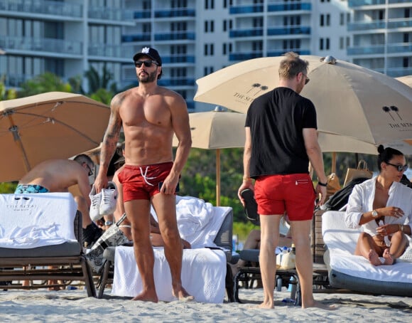 David Guetta et sa compagne Jessica Ledon, avec son ami le DJ Cédric Gervais et sa fiancée Adriana Gutierrez, se prélassent sur la plage du palace Setai à Miami, le 20 mars 2022. 