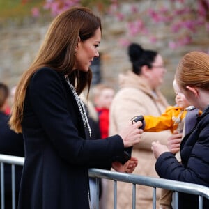 Le jeune Daniel Williams joue avec le sac à main de Catherine (Kate) Middleton, lors de sa visite au jardin commémoratif d'Aberfan, le 28 avril 2023.