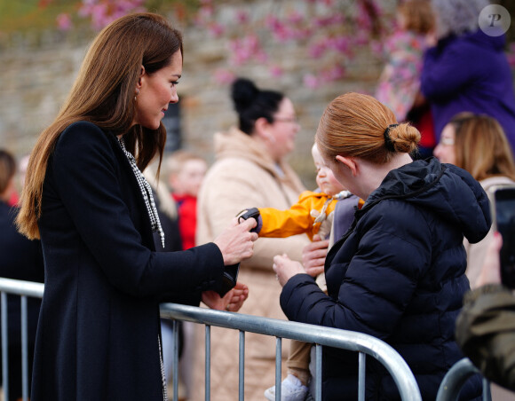 Le jeune Daniel Williams joue avec le sac à main de Catherine (Kate) Middleton, lors de sa visite au jardin commémoratif d'Aberfan, le 28 avril 2023.