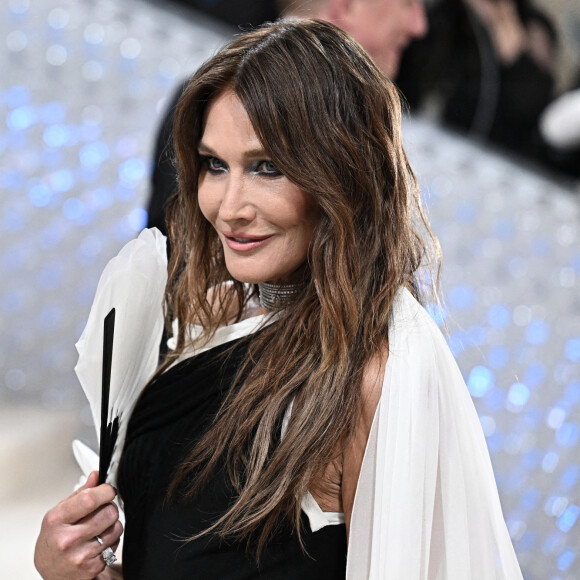 Vêtue d'une robe bicolore, noire et blanche, l'ancien top model a accessoirisé son look avec un éventail, qui n'est autre que l'accessoire préféré de son défunt ami.

Carla Bruni au MET Gala 2023 à New York le 1er mai 2023.
