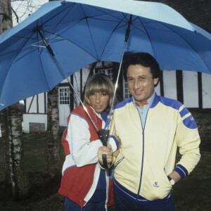 En France, Michel Drucker, avec sa femme Dany Saval, se promenant dans le jardin et s'abritant sous des parapluies © Michel Ristroph via Bestimage
